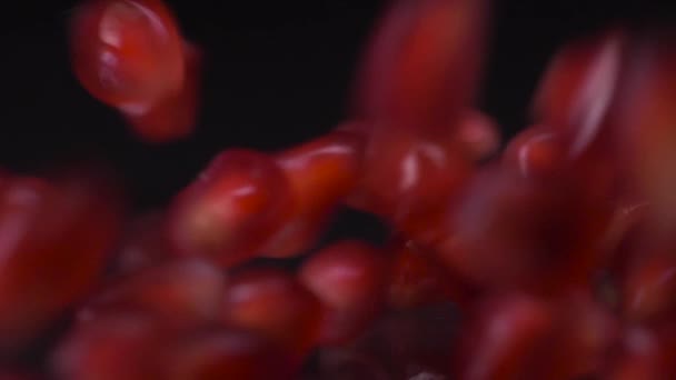 Κόκκινα κοσμήματα. Σούπερ αργή κίνηση shot από σπόρους ροδιού που πέφτουν και κυλούν πάνω από μαύρο φόντο. Οι κόκκοι ροδιού κλείνουν σε βίντεο 4K. Υγιεινή διατροφή, έννοια των φρούτων. — Αρχείο Βίντεο