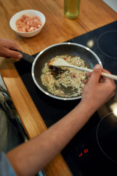 Κοντινό πλάνο του σοταρισμένου κρεμμυδιού και σκόρδου στο τηγάνι. Ο άνθρωπος ετοιμάζει δείπνο. Μαγειρική στο σπίτι έννοια — Φωτογραφία Αρχείου