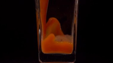 Meyve suyunu aç. Şeffaf bir bardağa siyah arkaplana domates suyu dökerken çekilen süper yavaş çekim. Kapatın. Sağlıklı içecek, vitamin konsepti