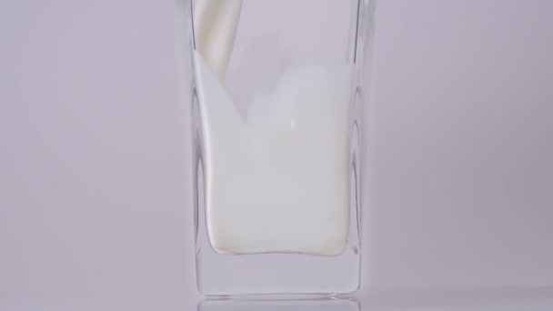 Dagelijkse dosis zuivel. Super slow motion shot van gieten, spetteren verse melk in een transparant glas tegen een witte achtergrond. Sluit maar af. Zuivelproductconcept — Stockvideo