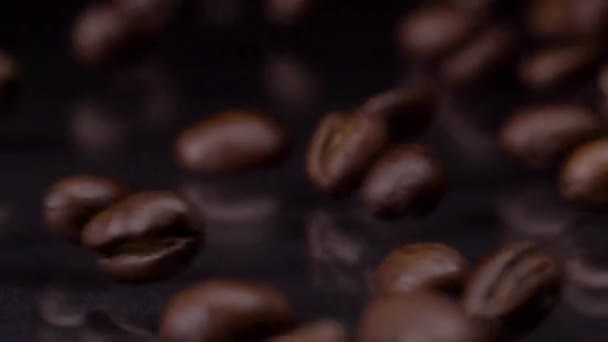 Not just any coffee. Slow motion shot of roasted brown coffee beans rolling, falling on dark background. Coffee grains close up 4K video. — Stock Video