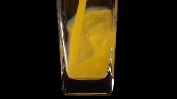 充满了水果。将橙汁倒入透明的玻璃杯中，在黑色背景下，动作非常缓慢。靠近点健康饮料、维生素、水果概念 — 图库视频影像