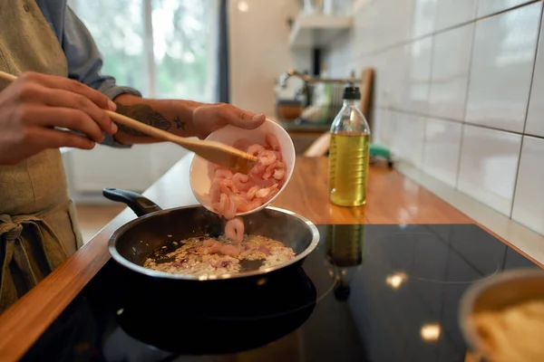 Közelkép az ember hozzá garnélarák pirított fokhagyma és hagyma a serpenyőben. Cook főzés étel tenger gyümölcsei. Mediterrán konyha koncepciója — Stock Fotó