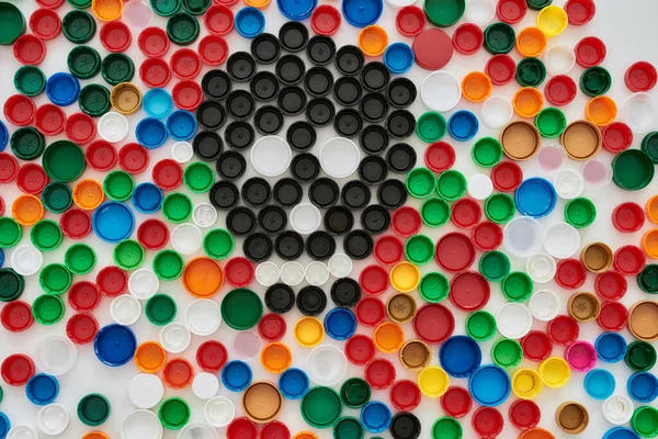 Flatlay collage with colorful plastic bottle caps and skull made of black caps on white background. Stop plastic pollution concept — Stock Photo, Image