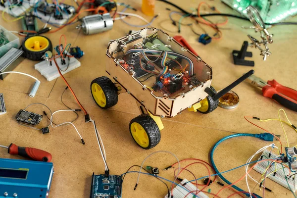 Kit de montagem de robô diy. Kit de componentes elétricos para a construção de dispositivos digitais. Peças de robótica e elementos deitados em uma mesa de madeira — Fotografia de Stock