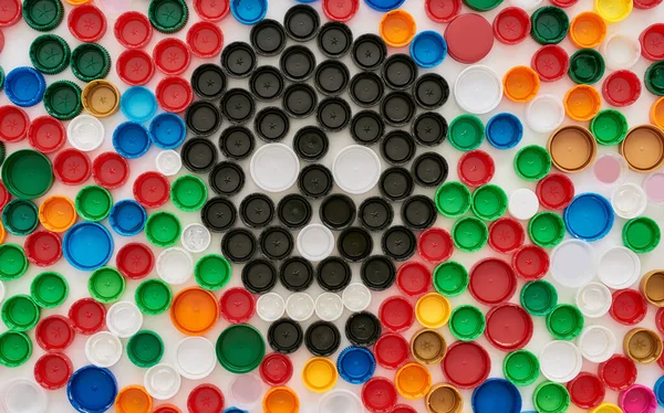 Flatlay collage with colorful plastic bottle caps and skull made of black caps on white background. Stop plastic pollution concept — Stock Photo, Image