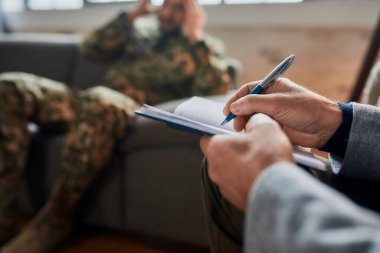 Hatıralar. Terapi seansı sırasında askerlerle iletişim kurarken not alan psikoloğun ellerini kapatın. Depresyon geçiren asker, psikolojik travma. Travma Sonrası Stres