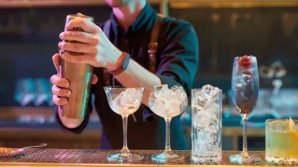 Prontos para todas as festas. Tiro recortado de barman masculino tremendo, misturando ingredientes ao fazer coquetel bebida alcoólica no balcão do bar na boate — Fotografia de Stock