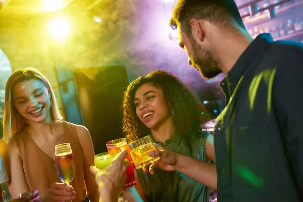 Un grupo de amigos, mujeres jóvenes y hombre charlando mientras se divierten, beber cócteles, pasar tiempo juntos en el club nocturno — Foto de Stock