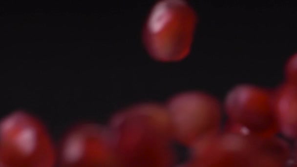 Het bevrijden van de zaden. Super slow motion shot van granaatappel zaden vallen en rollen over zwarte achtergrond. Granaatappelkorrels sluiten 4K video af. Gezond eten, fruitconcept. — Stockvideo