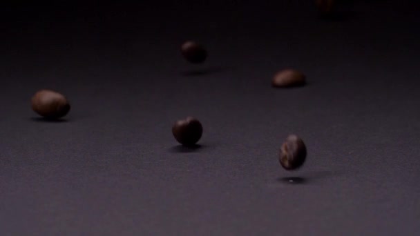 Pour le goût avec beaucoup de nuances. Plan au ralenti de grains de café brun torréfiés roulant, tombant sur fond sombre — Video