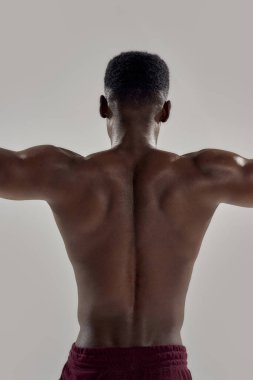 Kollarını açmış çıplak gövdesi olan kaslı Afrikalı Amerikalı bir adam. Yüzücü gri arka planda izole bir şekilde dalmak üzere. Spor, yüzme.