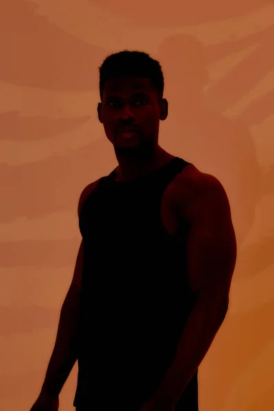 Silhouet van jonge gespierde Afro-Amerikaanse man die naar de camera kijkt, geïsoleerd poserend boven oranje creatieve kunstachtergrond met zebrapatroon. Sport, workout, bodybuilding concept — Stockfoto