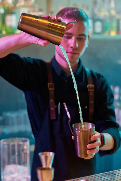 O barman faz melhor. Close up de barman masculino derramando, misturando ingredientes enquanto faz coquetel bebida alcoólica no balcão do bar na boate — Fotografia de Stock