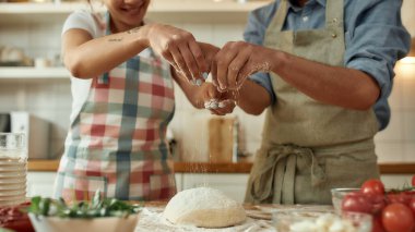 Çiftin hamuru hazırlarken kesilen görüntüsü. Önlüklü genç adam ve kadın evde pizza yapıyor. Hobi, yaşam tarzı