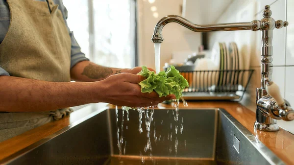 Erkeğin ellerini kapat, mutfaktaki lavaboda sebze pişirirken sebze yıka. — Stok fotoğraf