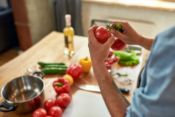 Közelkép az ember kezét, szakács gazdaság, eltávolítása szárak paradicsom, miközben készül az egészséges étel zöldségekkel a konyhában — Stock Fotó