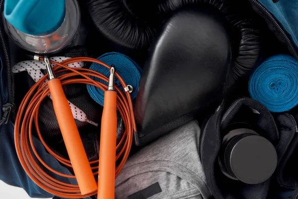 Close up shot of gym or training equipment. Boxing gloves, hand wraps, clothing, bottle of water and jumping rope