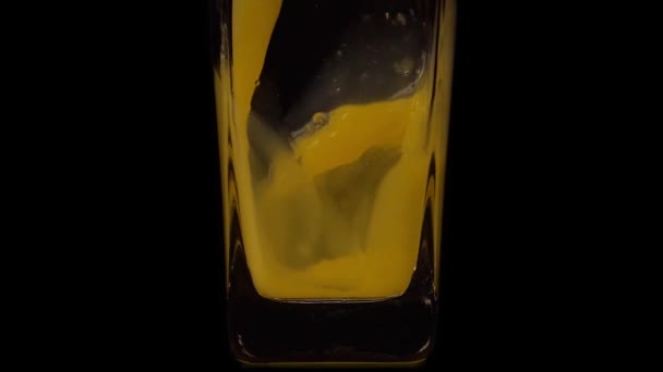 Pyszne w każdym łyku. Super slow motion shot wylewania soku pomarańczowego do przezroczystej szklanki na czarnym tle. Zamknij drzwi. Zdrowy napój, witaminy, koncepcja owoców — Wideo stockowe