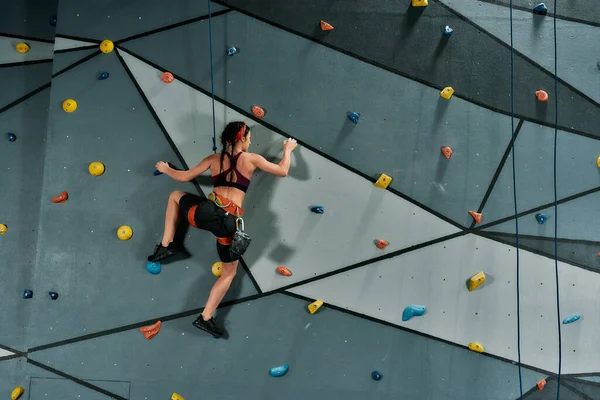 Mujer en equipo de seguridad y entrenamiento de arnés en la pared de escalada artificial en interiores —  Fotos de Stock