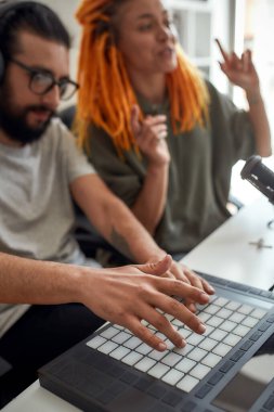 Teçhizat ve trampet makinesiyle müzik yapan adamın ellerine odaklan. Kadın ve erkek blogcular evde video blogu veya vlog kaydediyor