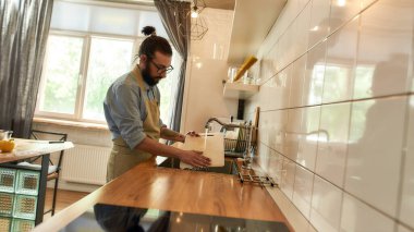 Genç adam, İtalyan aşçı sebze doğradıktan sonra lavaboda tahtaları yıkıyor.