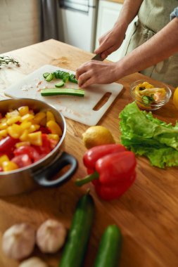 Sebze doğrayan ve sağlıklı yemek hazırlarken tencereye koyan bir adamın ellerini kapatın. Mutfakta çorba. İtalyan mutfağı kavramı