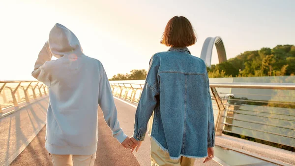 Lesbisch stel dat op de brug staat, hand in hand terwijl ze samen de zonsopgang bewonderen. Homoseksualiteit, LGBT en liefdesconcept — Stockfoto