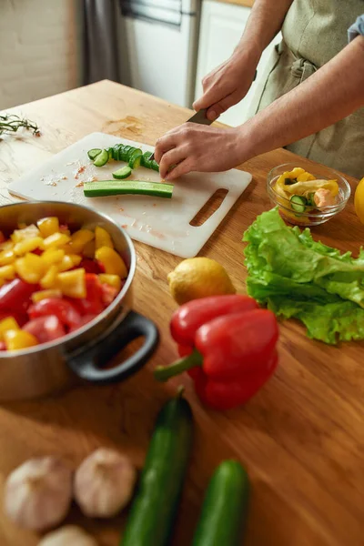 Κοντινό πλάνο χεριών ανθρώπου που κόβει λαχανικά και τα βάζει σε μια κατσαρόλα ενώ ετοιμάζει υγιεινό γεύμα, σούπα στην κουζίνα. Ιταλική κουζίνα έννοια — Φωτογραφία Αρχείου