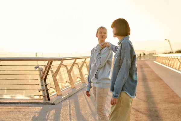 Felice coppia lesbica parlando mentre cammina sul ponte e guardando l'alba insieme. Omosessualità, LGBT e concetto di amore — Foto Stock