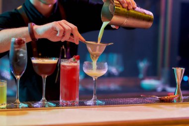 Buradaki en iyi alkol. Erkek barmenlerin bardakları doldurması, kokteyl hazırlarken malzemeleri karıştırması, gece kulübündeki barda alkollü içkiler.