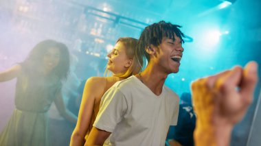 Çekici beyaz kadın ve karışık ırk adamı gülerken barda dans ediyorlar.