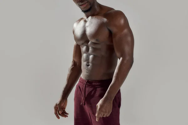 Gehakt schot van gespierde Afro-Amerikaanse man die zijn naakte romp laat zien terwijl hij hemdloos poseerde geïsoleerd over een grijze achtergrond. Sport, workout, bodybuilding concept — Stockfoto