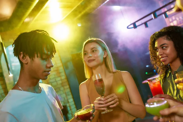En grupp vänner, unga kvinnor tittar på en kille medan de har roligt, dricker cocktails, tillbringar tid på nattklubben — Stockfoto