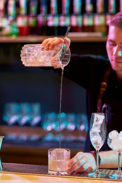 Close up das mãos do barman masculino derramando, misturando ingredientes enquanto faz coquetel clássico bebida alcoólica no balcão do bar na boate — Fotografia de Stock