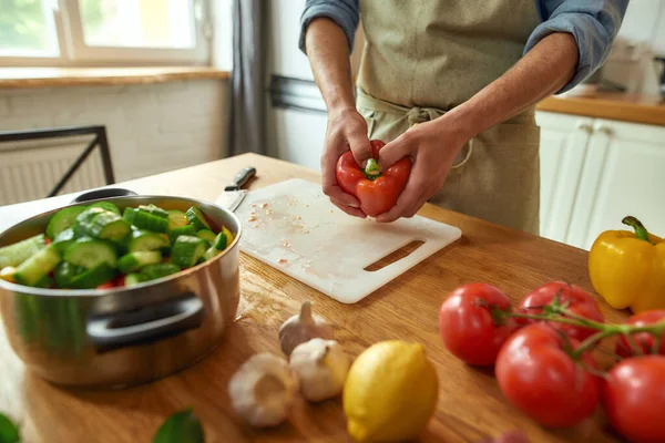 Közelkép az ember kezéről, amint paprikát készít az egészséges ételek főzéséhez, levest a konyhában. Olasz konyha koncepciója — Stock Fotó
