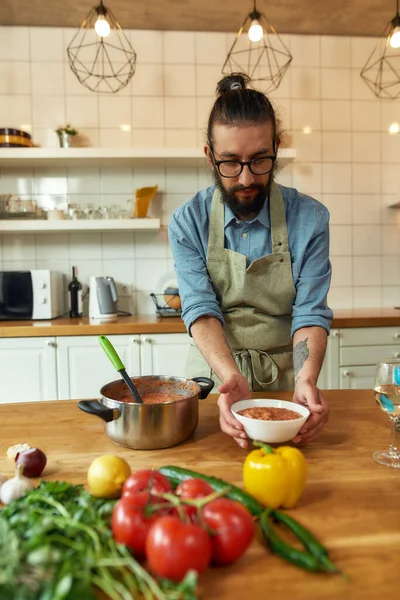 İtalyan adam masaya lezzetli bir çorba koyuyor. Mutfakta geleneksel yemeği pişir. Evde yemek, İtalyan mutfağı.