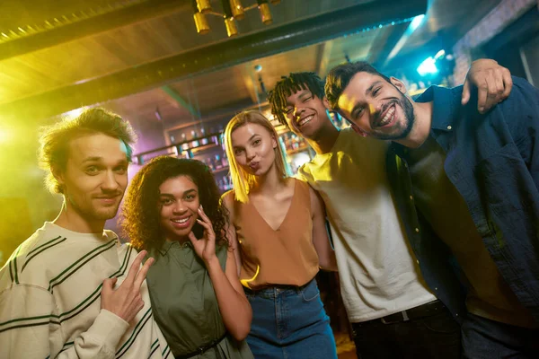 Gülümse. Kameraya bakıp gülümseyen genç kadın ve erkeklerin portresi. Çok ırklı bir arkadaş grubu barda takılıyor.