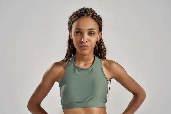 Gri arka planda izole bir şekilde poz verirken spor kıyafetli genç bir atletik sporcu kadın fitness takımının portresi. — Stok fotoğraf