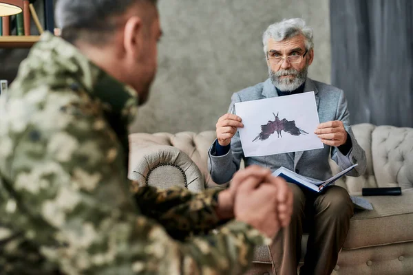 Volwassen psycholoog houdt foto met inktvlek, Rorschach Inkblot voor militaire man tijdens therapie sessie. Soldaat lijdt aan depressie, psychologisch trauma. PTSS-concept — Stockfoto