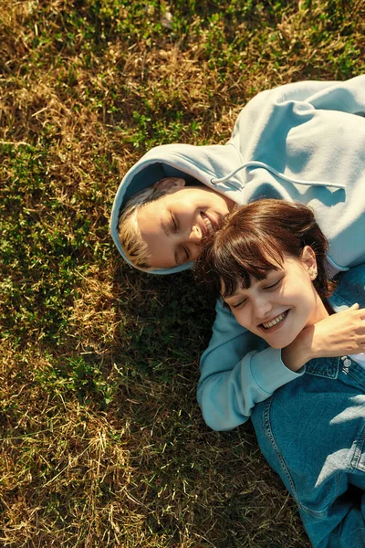 Mutlu lezbiyen kızlar yaz parkında çimlerin üzerinde yatıyor, aşıklar gülüyor, birlikte dışarıda vakit geçiriyorlar.