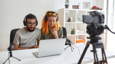 Birkaç blogcu, kulaklıklı genç adam ve kadın laptoptan bir şey izliyor, tepki videosu ya da vlog kaydederken surat yapıyor