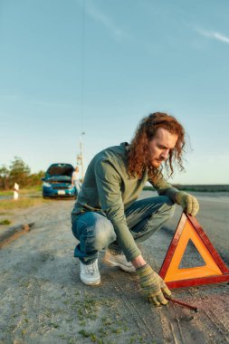 Şoför kırmızı uyarı üçgeni ya da acil durum dur işareti koyuyor yolun kenarına.