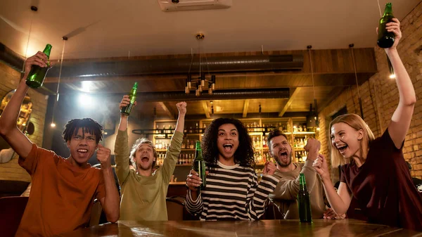 Grita. Amigos felices en el bar viendo partidos deportivos en la televisión juntos, bebiendo cerveza y celebrando la victoria. Gente, ocio, amistad y entretenimiento — Foto de Stock
