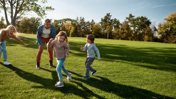 Felices recuerdos de infancia. Familia emocionada corriendo al aire libre en un día soleado — Foto de Stock