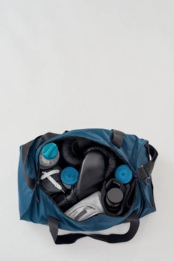 Eğitim ve egzersiz ekipmanları. Boks eldivenli bir spor çantasının üst görüntüsü, el kağıtları, giysiler, su şişesi ve gri arka planda izole edilmiş diğer şeyler.