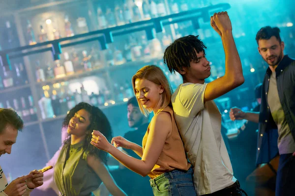 ¡Joy! Atractiva joven caucásica y chico de raza mixta disfrutando de la noche, bailando en la fiesta en el bar — Foto de Stock