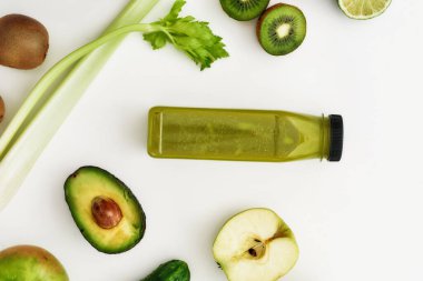 Beyaz arka planda izole edilmiş sağlıklı detoks suyu veya smoothie şişesiyle çeşitli yeşil meyve ve sebzelerin üst görünüm bileşimi
