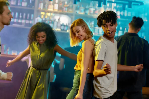 Atractiva joven caucásica y chico de raza mixta disfrutando de la noche, bailando en la fiesta en el bar — Foto de Stock