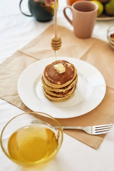 The process of adding honey on top of stack of sweet tasty pancakes on a plate, Process of preparing breakfast on the table — Stock Photo, Image